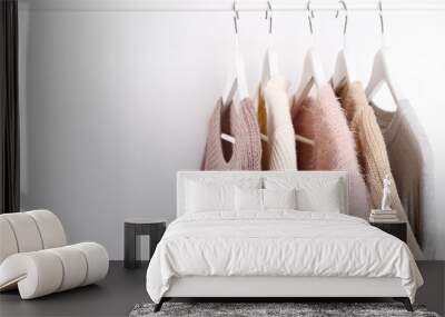 Warm knitted, autumn, winter clothes hanging on a rack, trending concept, pastel colors Wall mural