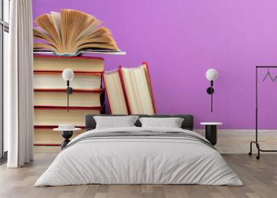 open book. Composition with hardback books, fanned pages on wooden deck table and purple background. Books stacking. Back to school. Copy Space. Education background. Wall mural