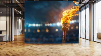 Blazing flame in olympic torch against blurred sports arena with copyspace for text placement  Wall mural