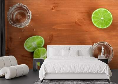 A photo of two tequila shots with limes, shot from above on a dark rustic wooden background, forming a frame for copy space Wall mural