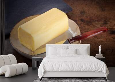 A stick of fresh butter with a knife on a plate, on a dark rustic wooden table Wall mural