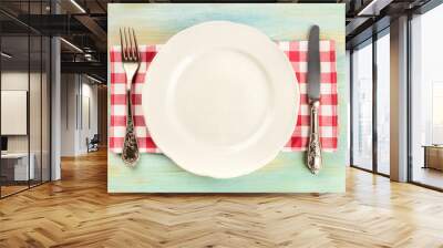 An overhead photo of a white plate with a fork and a knife on a teal background with copy space Wall mural