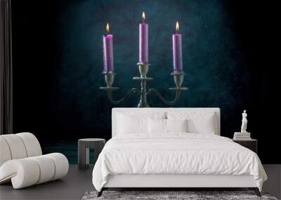 Candle magic. Burning candles in a vintage candle holder on a dark background, toned image Wall mural