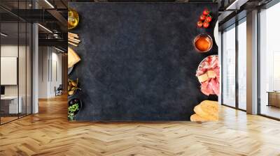 Italian food panorama with a place for text. Pizza, pasta, cheese, hams, olives and olive oil, and wine, overhead shot on a black background, a frame, a flat lay design template for a restaurant menu Wall mural