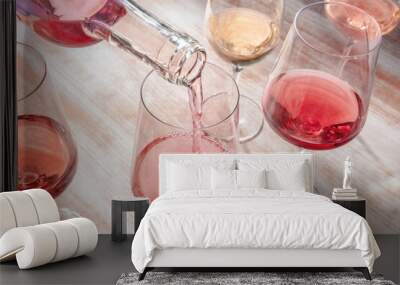 Pouring rose wine, glasses of various wine on a wooden table Wall mural