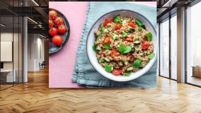 Quinoa tabbouleh salad in a bowl panorama, a healthy dinner with tomatoes and mint, overhead flat lay shot with a drink on a pink background Wall mural