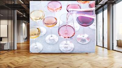 Rose wine pour into a glass at a tasting. Rose, red, and white wine, drinks on a table at a winery. An assortment of wines of many different colors and hues Wall mural