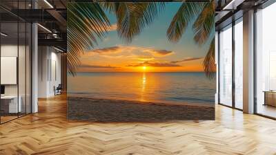 A vibrant orange sunset over a calm tropical ocean seen through palm leaves. Wall mural