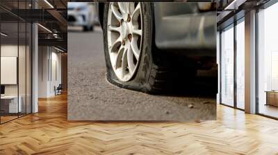 Car wheel with a flat tire on the roadway. Image of an accident, damage, breakdown for illustration on the topic of repair, insurance. Selective focus. Wall mural