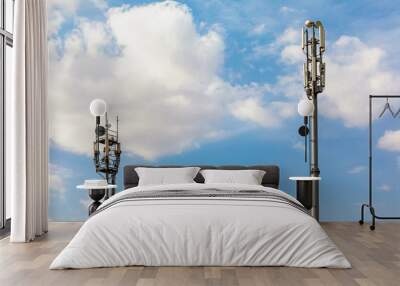 Two telecommunications towers with 4G, 5G transmitters. cellular base station with transmitting antennas on a telecommunications tower against a blue sky with clouds. Wall mural