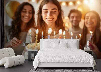 a group of friends celebrating a birthday with a cake and lit candles. Wall mural