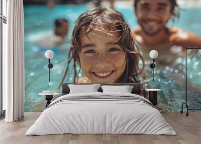 A cheerful young girl enjoys the water with a blurred male figure in the background, exuding summer joy Wall mural