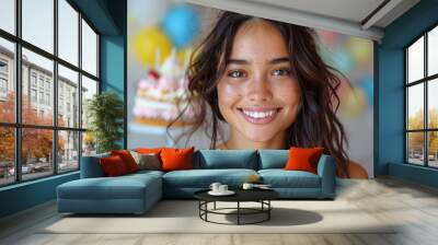 A cheerful young woman with freckles, a birthday hat, and a cake is smiling at the camera Wall mural