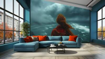 A moment of introspection is captured as a woman with windswept hair stares out at the churning ocean below an ominous clouded sky Wall mural