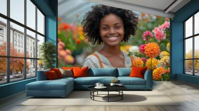 A radiant young woman with a bright smile surrounded by colorful dahlia flowers in a greenhouse Wall mural