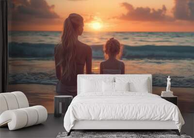 A young mother and her daughter stand on the shore, their clothing rustling in the gentle ocean breeze as they watch the vibrant sky transform into a fiery canvas, creating a picturesque sunset on th Wall mural