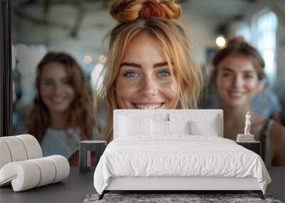 Portrait of a joyful young woman with freckles and red hair bun, two smiling friends in soft focus behind her Wall mural