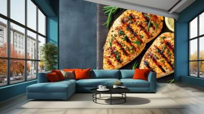 Two juicy grilled chicken breasts are paired with a lemon slice and sprigs of rosemary, creating an enticing dish that promises exquisite flavor and aroma. Wall mural