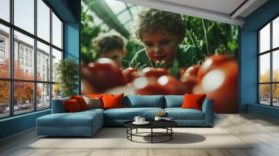 Two young children are captivated as they examine ripe red tomatoes closely in a lush greenhouse environment, embodying curiosity and discovery in nature. Wall mural