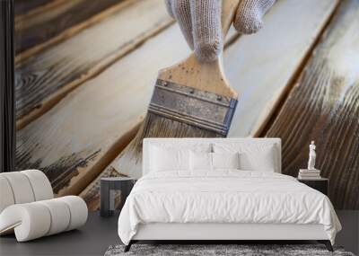 Hand with brush paints the wooden floor with white paint Wall mural