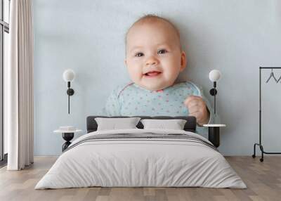 Portrait of a smiling baby in bed. Baby smiling and looking up to camera. Good morning! Wall mural