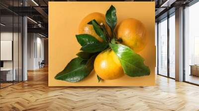 ripe mandarin or tangerine fruit with green leaves over yellow background. Wall mural