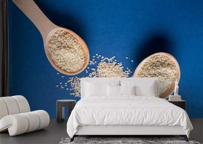 Two wooden spoons with white Flax seeds on blue background, flat lay. Wall mural