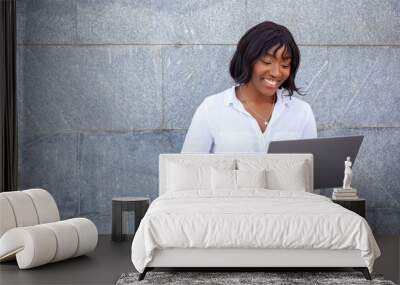 Image of optimistic African American female with happy face using laptop computer for work remotely outdoors, posing over gray background. Empty copy space. Wall mural