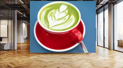 Cup of matcha latte in red cup on blue background in a cafe with copy space. High quality photo. Wall mural