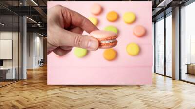 Hand holding Sweet and colourfull french macaroons or macaron on pink background Wall mural