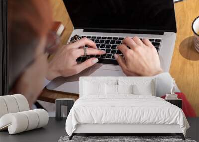 Shot of an attractive mature businesswoman in red suit working on laptop in her workstation. Wall mural