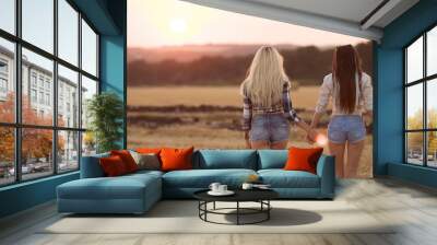 Two playful young women having fun outdoors at sunset light. Strong sun glare Wall mural