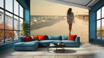 Beautiful young woman walking along the beach, woman enjoying the view of the sea  Wall mural