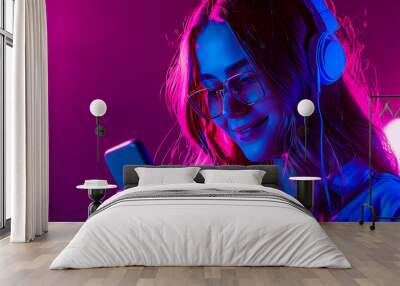 Happy young pretty girl with cellphone on dark background in purple neon light.  Wall mural