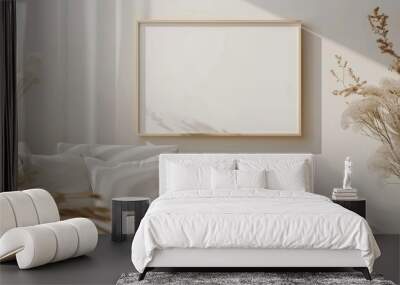 Blank landscape frame mockup on a white wall surrounded by furniture and a dried gypsophila plant for decor. The interior has a minimalistic design with an artwork mockup. Wall mural