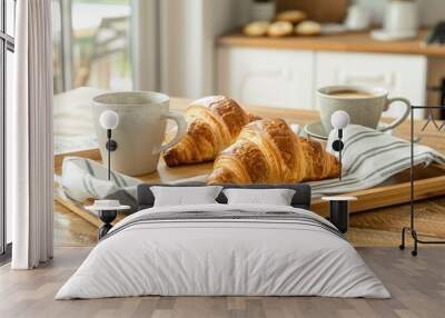 Croissants and coffee on bamboo tray with striped cotton towel on wooden table in kitchen. Wall mural