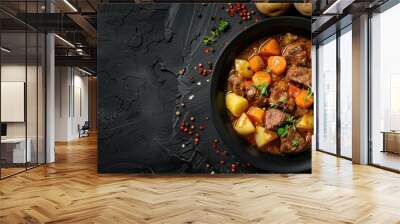 Top view of a black background with copy space showcasing beef stew accompanied by potatoes, carrots, and herbs Wall mural