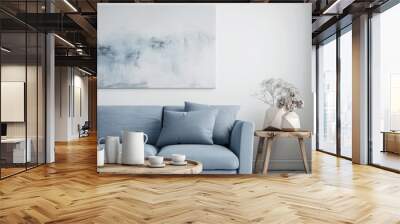 Two mugs on a wooden table in a white living room with a blue sofa and a silver painting Wall mural