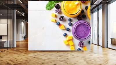 Yellow and purple fruit smoothies are displayed in glass jars with straws, mint leaves, mango slices, and berries on a decorative border.  Wall mural