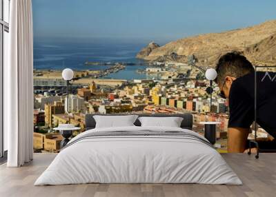 Man wearing black t-shirt watching from above, the port and the city of Almeria, Spain Wall mural