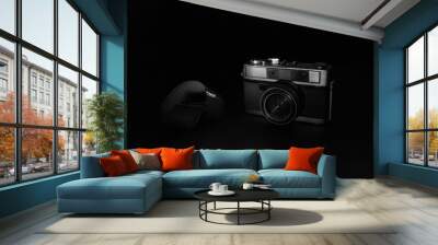 Old camera and film reel on black background Wall mural