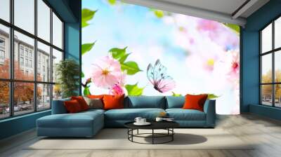 Beautiful butterfly and cherry blossom branch in spring on blue sky background with copy space, soft focus. Amazing elegant artistic image of spring nature, frame of pink Sakura flowers and butterfly. Wall mural