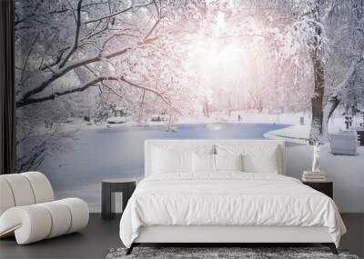 Beautiful natural landscape of a snowy city park with snow-covered trees and frozen pond on bright winter day. Wall mural