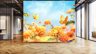 Bright colorful summer spring flower border. Natural landscape with many orange lantana flowers and fluttering butterflies Lycaena phlaeas against blue sky on sunny day. Wall mural