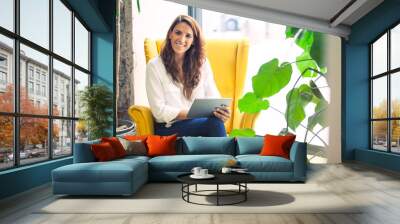 Portrait of a successful startup founder in the couch of her office, holding a tablet device.  Wall mural