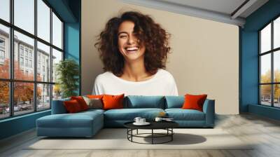 A beautiful woman wearing casual clothing, radiating joy with a bright smile in a studio setting, ideal for banners and advertisements Wall mural