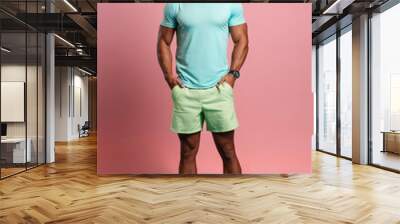 Full length portrait of a smiling young man in sportswear standing with hands in pockets isolated over pink background Wall mural