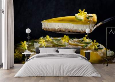 Piece of delicious homemade lemon cheesecake with lime and lemon slices Garnished with yellow flowers and green verbena leaves and coconut flakes.  Wall mural