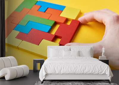 Logical thinking and finishing task concept. Woman hand adding last missing wooden block to finish puzzle Wall mural