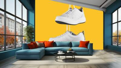 Pair of white male sneakers on yellow background. Wall mural